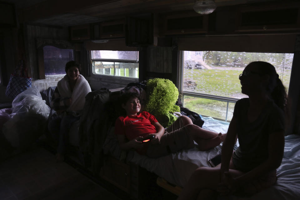 As rain pours and thunder rolls outside their temporary trailer home, Chief Shirell Parfait-Dardar of the Grand Caillou/Dulac Band of Biloxi-Chitimacha-Choctaw Indians, right, laughs while talking with her kids, Aralyn Dardar, left, and Dale Dardar Jr., center, in Chauvin, La., on Tuesday, Sept. 28, 2021. Their home was one of dozens destroyed by Hurricane Ida, which made landfall in late August. (AP Photo/Jessie Wardarski)