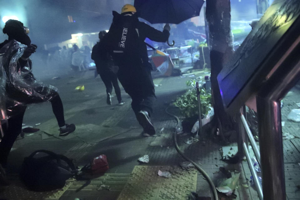 Protesters run outside of Hong Kong Polytechnic University as police storm the campus in Hong Kong, early Monday, Nov. 18, 2019. Fiery explosions were seen early Monday as Hong Kong police stormed into a university held by protesters after an all-night standoff. (AP Photo/Kin Cheung)