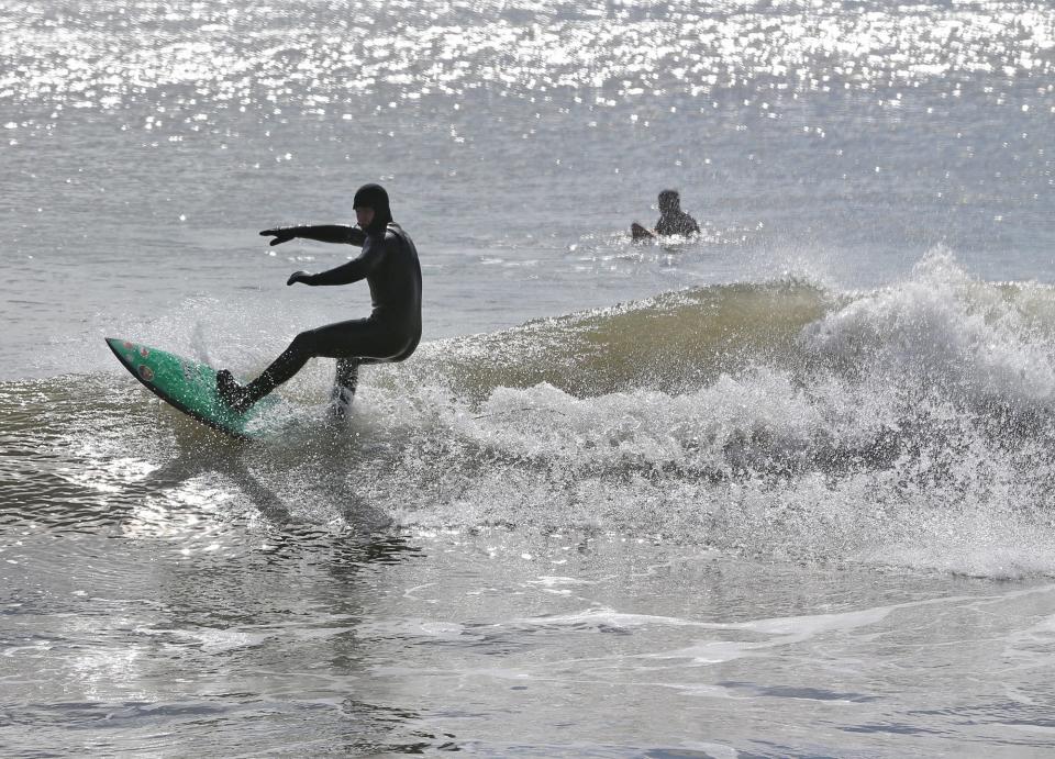 Surfers ride some waves due to strong winds during high tide at North Hampton State Beach March 11, 2024.