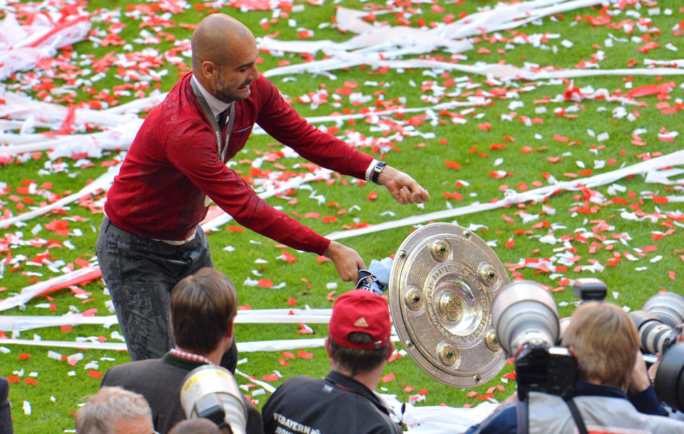 As Bayern head coach Pep Guardiola tries to pose for the photographers as the trophy falls down after Bayern Munich won the Bundesliga Championships in the Allianz Arena in Munich, Germany, on Saturday, May 10. 2014. (AP Photo/Kerstin Joensson)