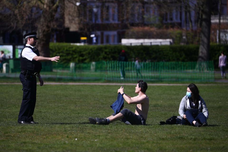 A police officer speaks with people in Greenwich Park (REUTERS)