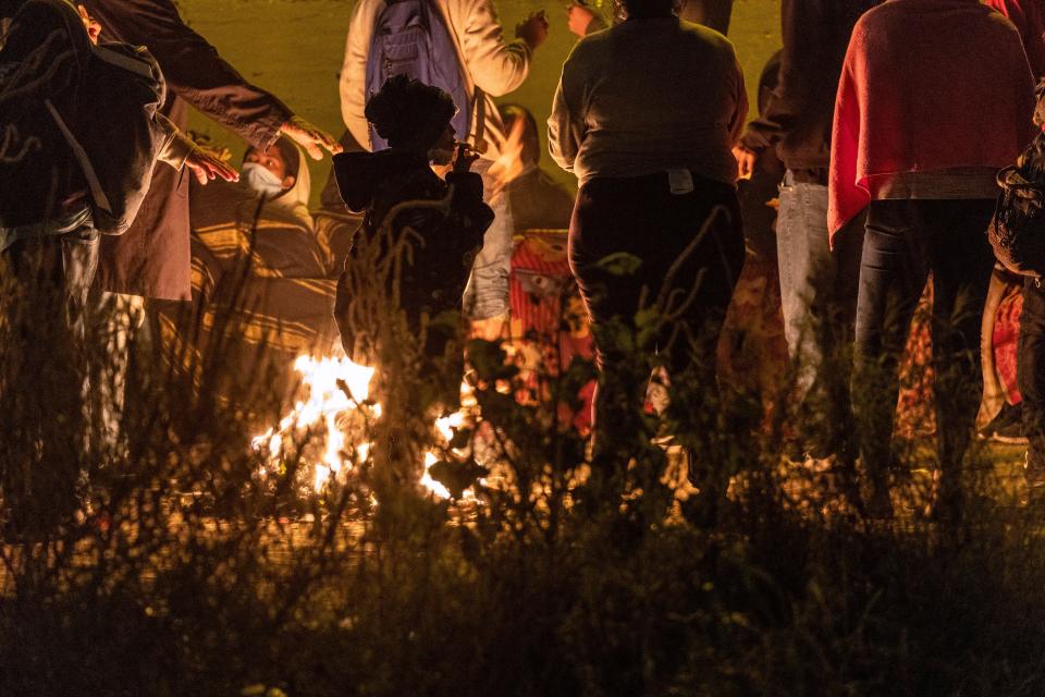 Migrants warm by a fire after crossing the Rio Grande into El Paso, Texas, to request asylum on Dec. 19, 2022, as seen from Ciudad Juarez, Mexico. U.S. Supreme Court Chief Justice John Roberts issued an "administrative stay," temporarily leaving the Title 42 pandemic era policy in place to quickly expel migrants at the border. Border officials expect an even larger migrant surge at the border if and when Title 42 is lifted.