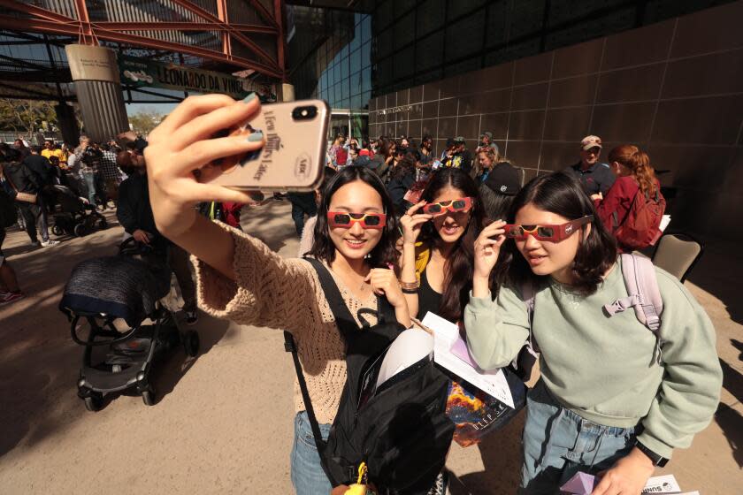 LOS ANGELES,CA APRIL 8, 2024 - From left, Sunwoo Neo, Taara Bhojwani & Hannah Chu all USC students, were part of the crowd that gathered at the California Science Center wearing protective eye-wear and starring skyward to view a partial solar eclipse on Monday, April 8, 2024. Southern California was far from the ``path of totality'' that saw the sun completely blocked out in some other parts of the country. (Al Seib / For The Times)