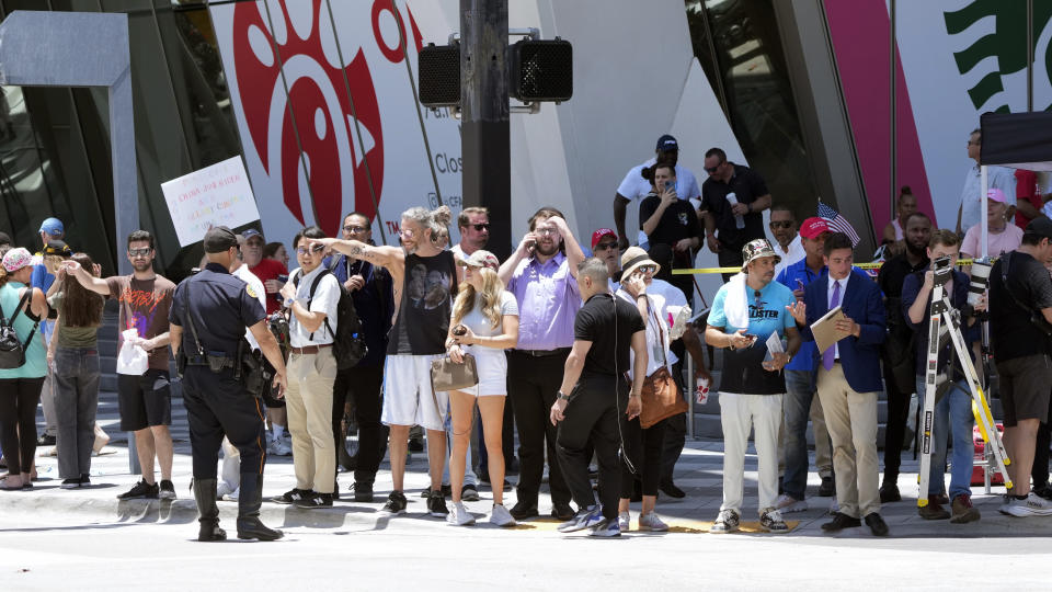 People watch as the motorcade carrying former President Donald Trump arrives at the Wilkie D. Ferguson Jr. U.S. Courthouse, Tuesday, June 13, 2023, in Miami. Trump is making a federal court appearance on dozens of felony charges accusing him of illegally hoarding classified documents and thwarting the Justice Department's efforts to get the records back. (AP Photo/Wilfredo Lee)