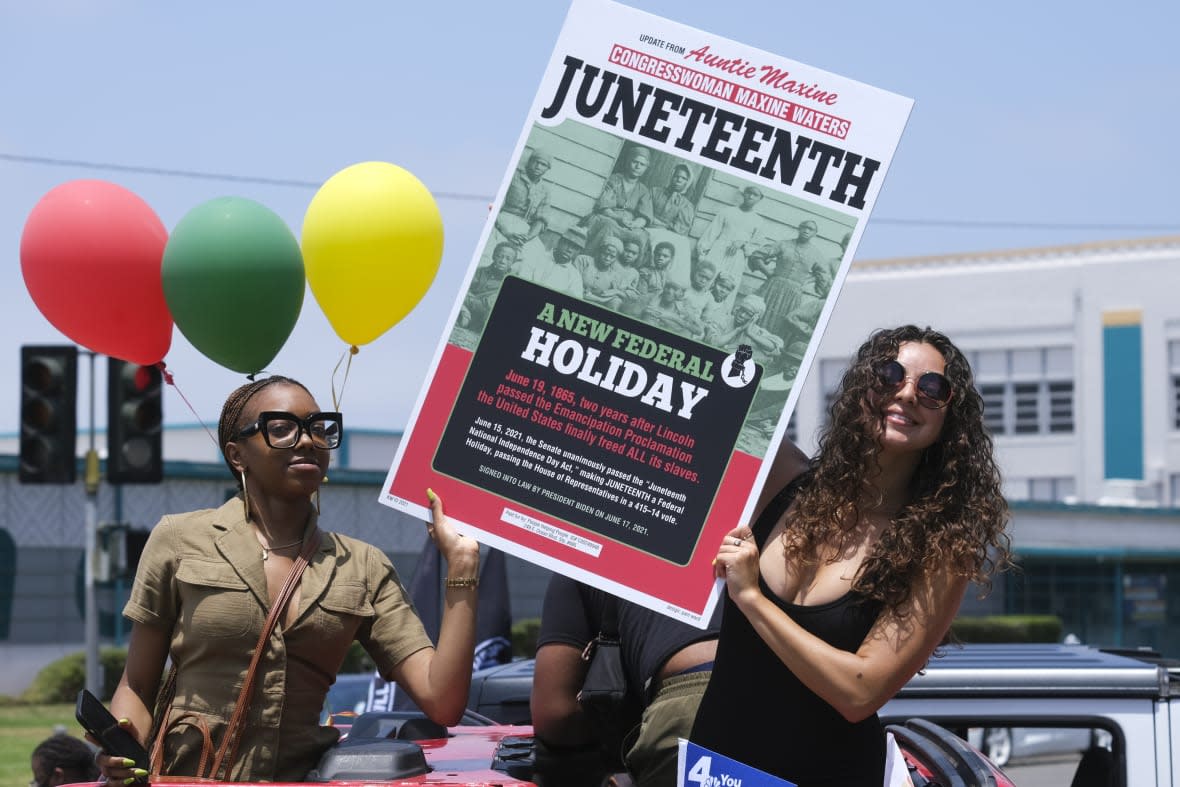 People hold a sign in their car during a car parade to mark Juneteenth on June 19, 2021, in Inglewood, Calif. (AP Photo/Ringo H.W. Chiu, File)