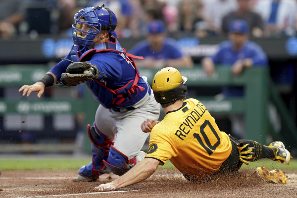 Pittsburgh Pirates' Bryan Reynolds (10) slides into home plate to score against Chicago Cubs catcher Yan Gomes, left, on a fielder's choice hit into by Joshua Palacios in the first inning of a baseball game in Pittsburgh, Friday, Aug. 25, 2023. (AP Photo/Matt Freed)