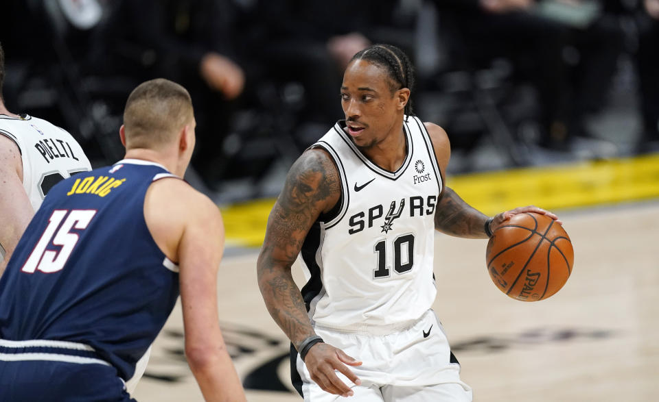 San Antonio Spurs forward DeMar DeRozan, right, looks to pass the ball as Denver Nuggets center Nikola Jokic defends in the first half of an NBA basketball game Friday, April 9, 2021, in Denver. (AP Photo/David Zalubowski)