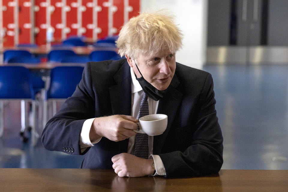 Britain's Prime Minister Boris Johnson drinks a coffee while speaking with pupils after taking part in a science lesson, during a visit to King Solomon Academy in London, Thursday April 29, 2021.  (Dan Kitwood/Pool via AP)