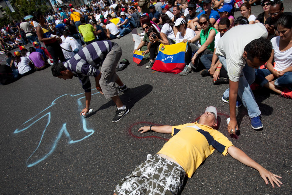 Demonstrators paint their silhouettes during a protest asking for the disarmament of armed groups in Caracas, Venezuela, Sunday, Feb. 16, 2014. For the past several days, protests have rocked Caracas yielding several dead and scores of wounded in clashes between opposition protesters with security forces and pro-government supporters. (AP Photo/Alejandro Cegarra)