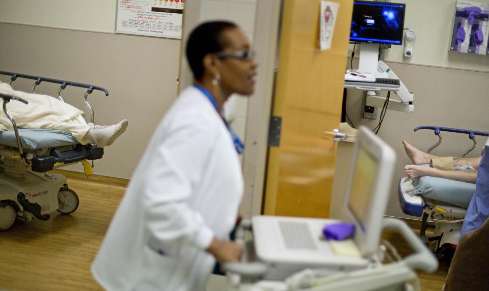 In this Friday, Jan. 24, 2014 photo, patients lie on beds in exam rooms as EKG Technician Gwendolyn Freeman makes her rounds at Grady Memorial Hospital, in Atlanta. In two years, federal payments to hospitals treating a large share of the nation’s poor will begin to evaporate under the premise that more people than ever will have some form of insurance under the federal health care law. The problem is that many states have refused to expand Medicaid, leaving public safety net hospitals there in a potentially precarious financial situation and elected officials facing growing pressure to find a fiscal fix. And in an election year, Democrats are using the decision by Republican governors not to expand Medicaid as a major campaign issue and arguing the hospital situation could have been avoided. (AP Photo/David Goldman)