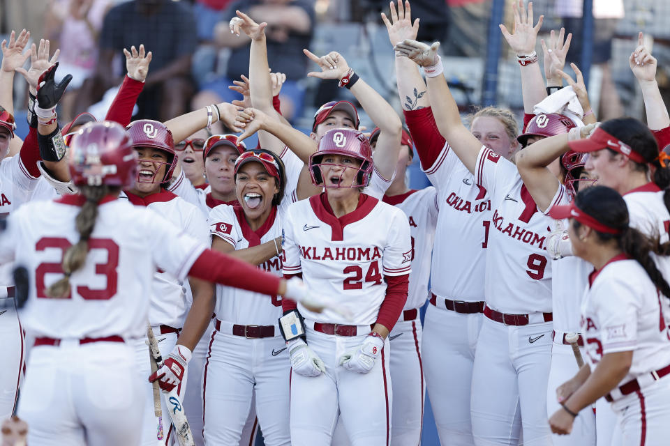 Oklahoma players wait for Tiare Jennings (23) at home plate after she hit a home run against against Texas during the first inning of Game 1 of the NCAA Women's College World Series softball championship series Wednesday, June 5, 2024, in Oklahoma City. (AP Photo/Alonzo Adams)