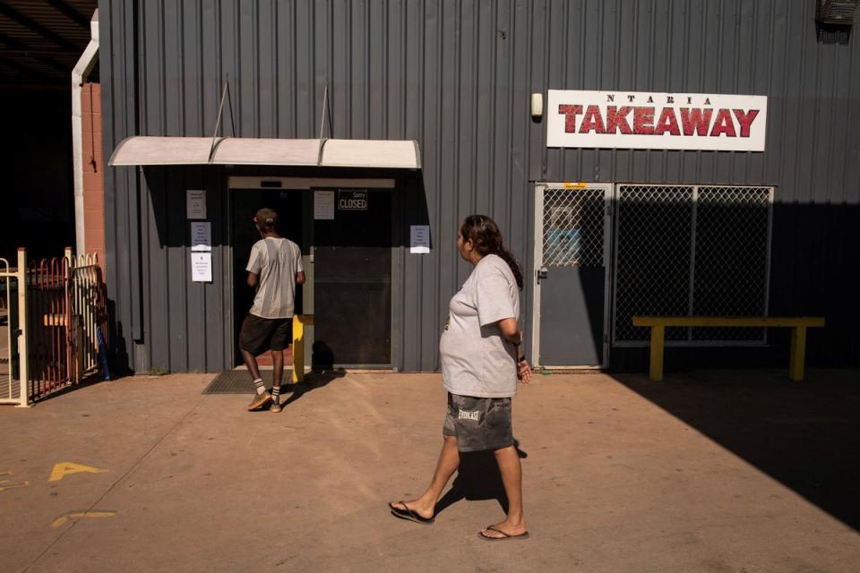 Local residents Jonathan and Rosemary walk by the takeaway shop in Hermannsburg (Reuters)