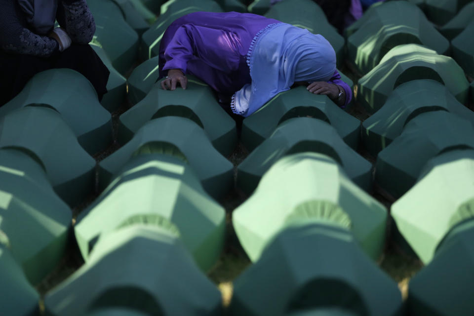 FILE - In this Monday, July 11, 2016 file photo, a Bosnian woman prays next to a coffin containing the remains of her relative perished in the Srebrenica massacre, during a funeral ceremony for the 127 victims at the Potocari memorial complex near Srebrenica, 150 kilometers (94 miles) northeast of Sarajevo, Bosnia and Herzegovina. A Bosnian Serb leader has wrongly called the 1995 Srebrenica massacre, where over 8,000 Muslim men and boys were killed by Bosnian Serb troops, "a fabricated myth." Milorad Dodik, head of Bosnia's multi-ethnic joint presidency, spoke during a conference discussing war crimes. His comments defy international court rulings that said genocide was committed in the eastern Bosnian enclave and have angered Bosnian Muslims. (AP Photo/Amel Emric, File)