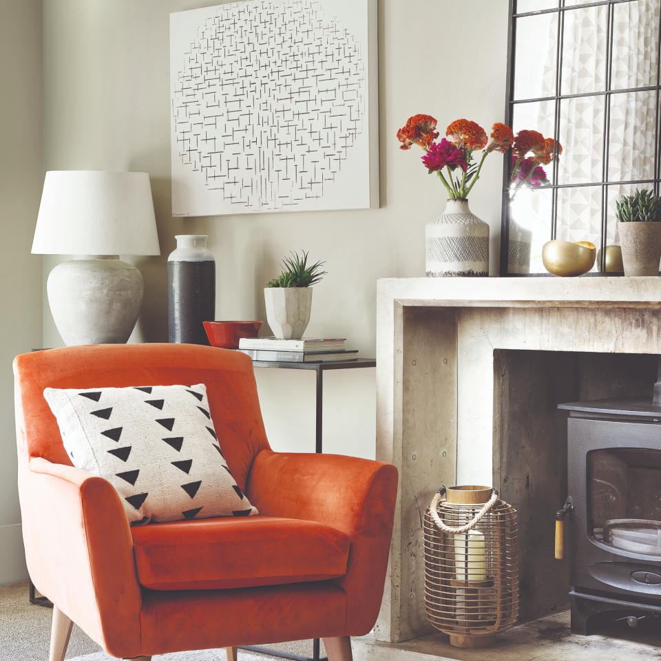 Stove fireplace with white mantlepiece, topped with vase of pink flowers