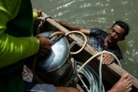 Wearing shorts and T-shirt, Bhoomin Samang jumps off his motorised skiff into Bangkok's Chao Phraya river -- strewn with city sewage and debris