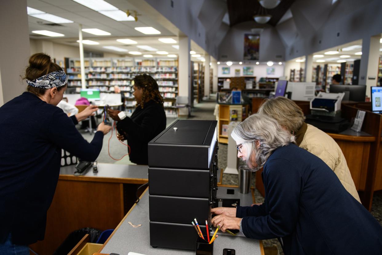 Librarian Missy Miller helps a woman help charge her cellphone at Southern Pines Public Library on Tuesday, Dec. 6, 2022. Power is out in parts of Moore County due to an attack on power substations on Saturday night.