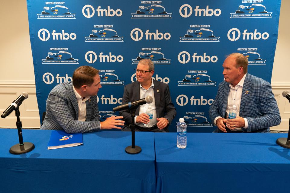 From left, Kansas athletics director Travis Goff, Kansas chancellor Douglas Girod and football coach Lance Leipold talk amongst themselves following Tuesday's press conference for the Gateway District.
