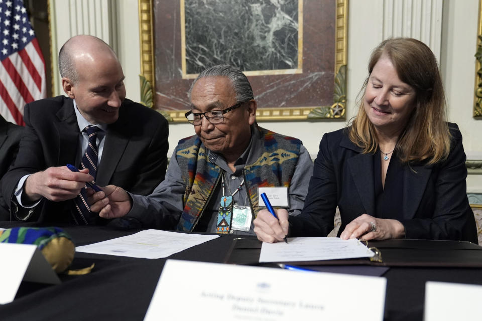 Chair Gerry Lewis of the Yakama Nation, center, hands a pen to Deputy Secretary of Energy David Turk, left, as Acting Deputy Secretary of the Interior Laura Daniel-Davis signs a document during a signing ceremony in Washington, Friday, Feb. 23, 2024. The ceremonial signing is an agreement between the Biden administration and state and Tribal governments to work together to protect salmon and other native fish, honor obligations to Tribal nations, and recognize the important services the Columbia River System provides to the economy of the Pacific Northwest. (AP Photo/Susan Walsh)