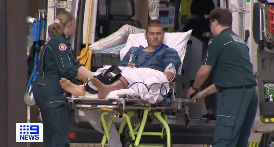 A shark attack victim is taken out of the back of an ambulance in a stretcher.