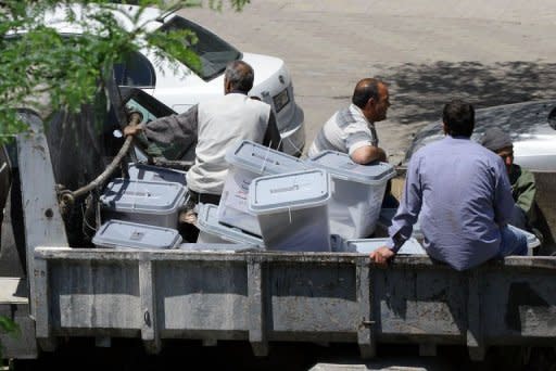 Syrian officials carry ballot boxes to a counting center in Damascus, one day after Syrians voted in the country's first "multiparty" parliamentary elections in five decades, dismissed by the opposition as a sham