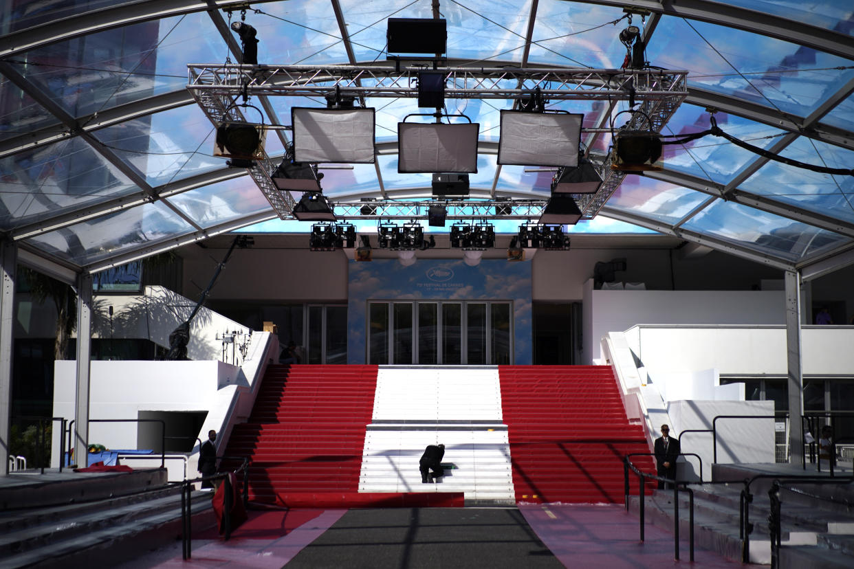 Crew members install the red carpet at the Palais des Festivals ahead of the opening day of the 75th international film festival, Cannes, southern France, Tuesday, May 17, 2022. The Cannes film festival runs from May 17 until May 28 2022. (AP Photo/Daniel Cole)