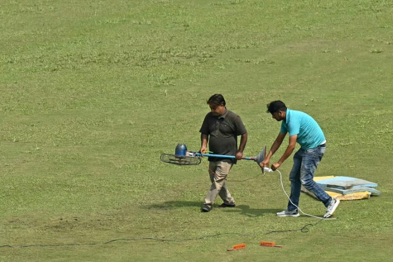 Groundsmen use a fan to dry a patch of wet outfield (Money SHARMA)