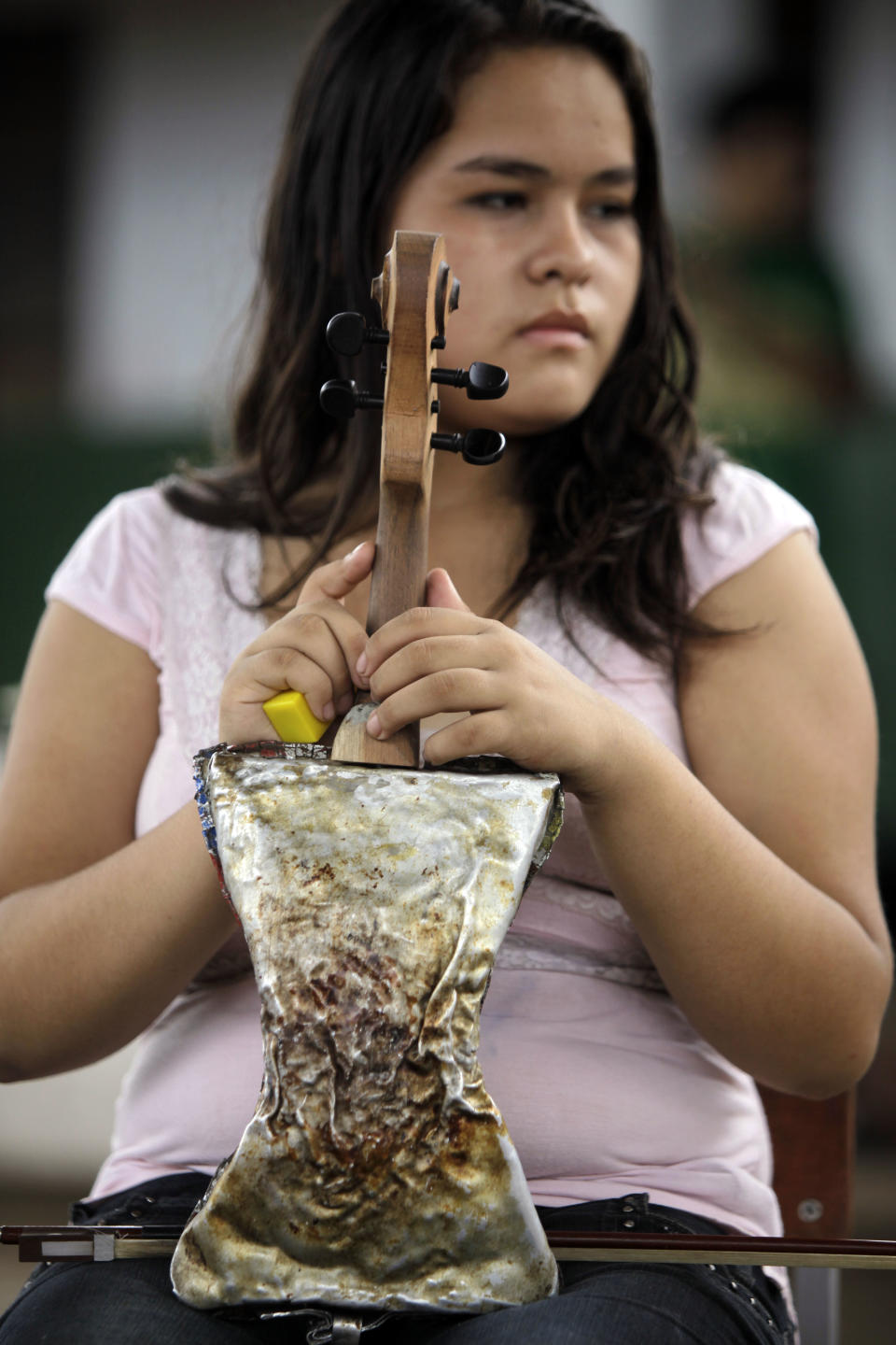In this Dec. 11, 2012 photo, musician Maria Rios, 16, holds her violin made of recycled materials before practicing with “The Orchestra of Instruments Recycled From Cateura” in Cateura, a vast landfill outside Paraguay's capital of Asuncion, Paraguay. “My mother signed me up in teacher Chavez's school three years ago. I was really bothered that she hadn't asked me first, but today I'm thankful because she put my name in as someone who wanted to learn violin,” Maria said. (AP Photo/Jorge Saenz)