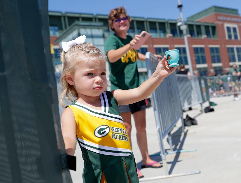 Aria Rubens, a 2½-year-old from De Pere, offers pretend tea from her Disney princess teacups to Green Bay Packers players after training camp on Aug. 10, 2022, in Green Bay, Wis.