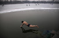 A swimmer dives into the icy water of the Houhai Lake in central Beijing, February 16, 2013. REUTERS/Petar Kujundzic (CHINA - Tags: SOCIETY ENVIRONMENT TPX IMAGES OF THE DAY) - RTR3DV01