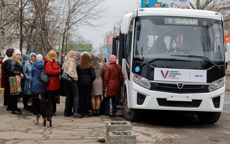 Votantes se reúnen frente a un colegio electoral móvil situado en un autobús, en el último día de las elecciones presidenciales rusas en el curso del conflicto entre Rusia y Ucrania en Makiivka (Makeyevka) en la región de Donetsk, Ucrania controlada por Rusia