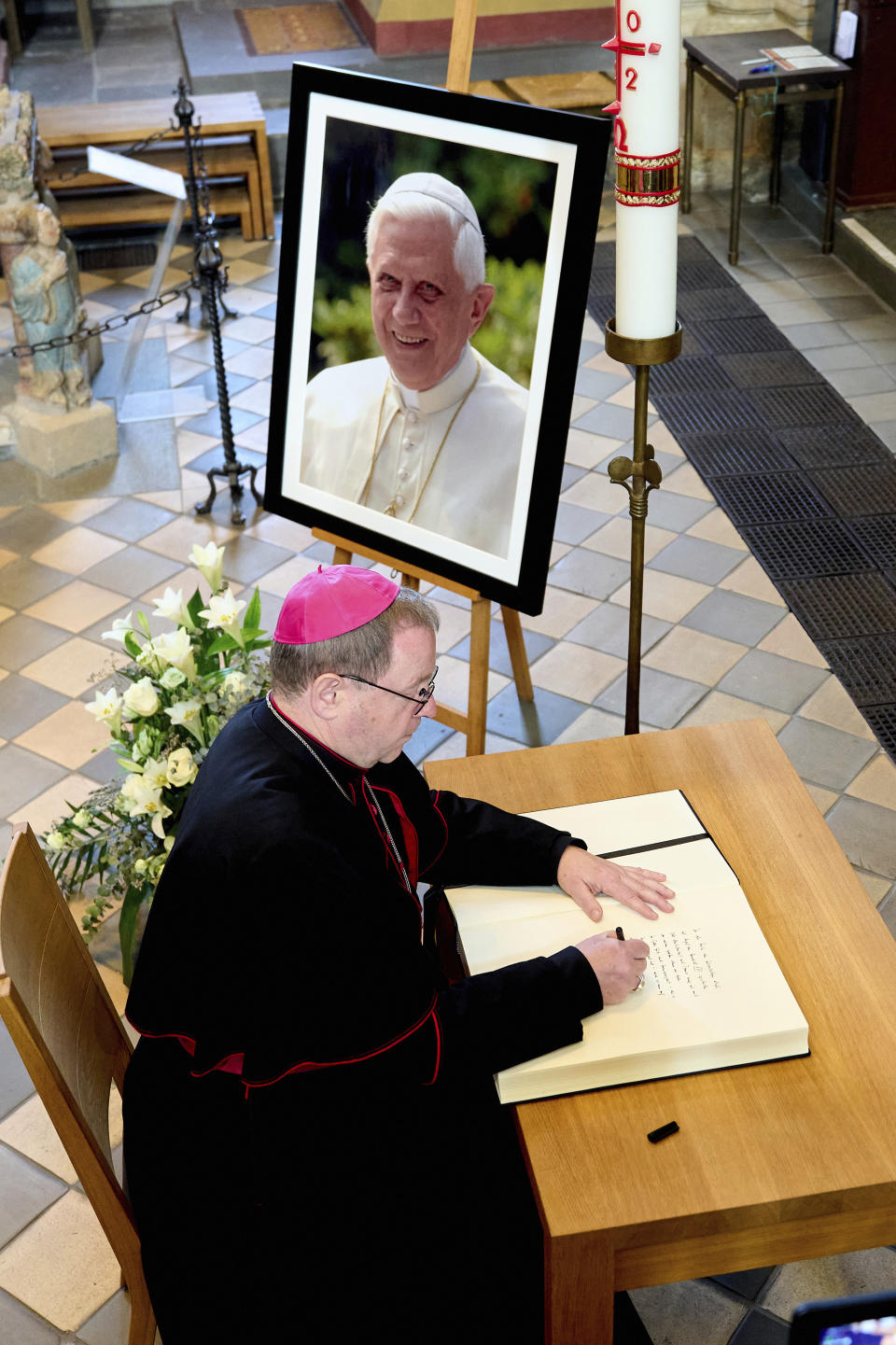 Bishop Georg Baetzing, head of the German Bishops' Conference, signs the book of condolence for Pope Emeritus Benedict at the Limburg Cathedral in Limburg, Germany, Saturday, Dec. 31, 2022. Pope Emeritus Benedict XVI, the German theologian who will be remembered as the first pope in 600 years to resign, has died, the Vatican announced Saturday. He was 95. (Thomas Frey/dpa via AP)
