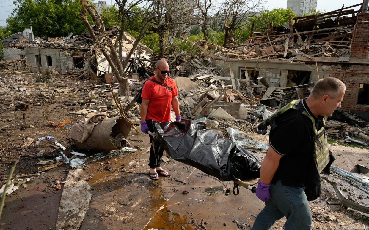 Criminologists carry the body of an elderly man after an aerial bombardment by Russia in Kharkiv on Sunday