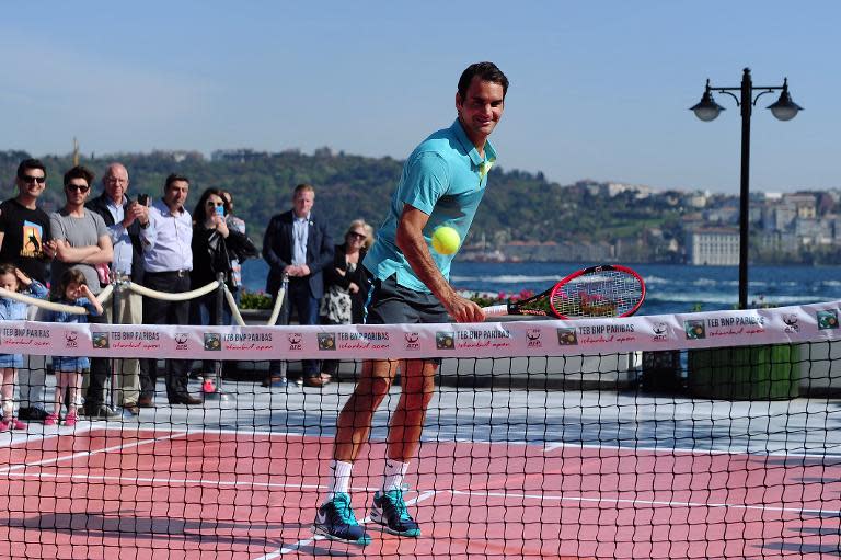 Swiss player Roger Federer returns the ball to a young Turkish tennis player during an exhibition tennis match after a press conference at the ATP Istanbul Open in Istanbul on April 27, 2015