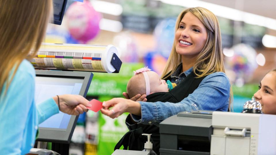 Mid adult Caucasian woman is shopping local grocery store or supermarket with elementary age daughter and infant, fees, America, money, payment, avoid fees, bills, debt