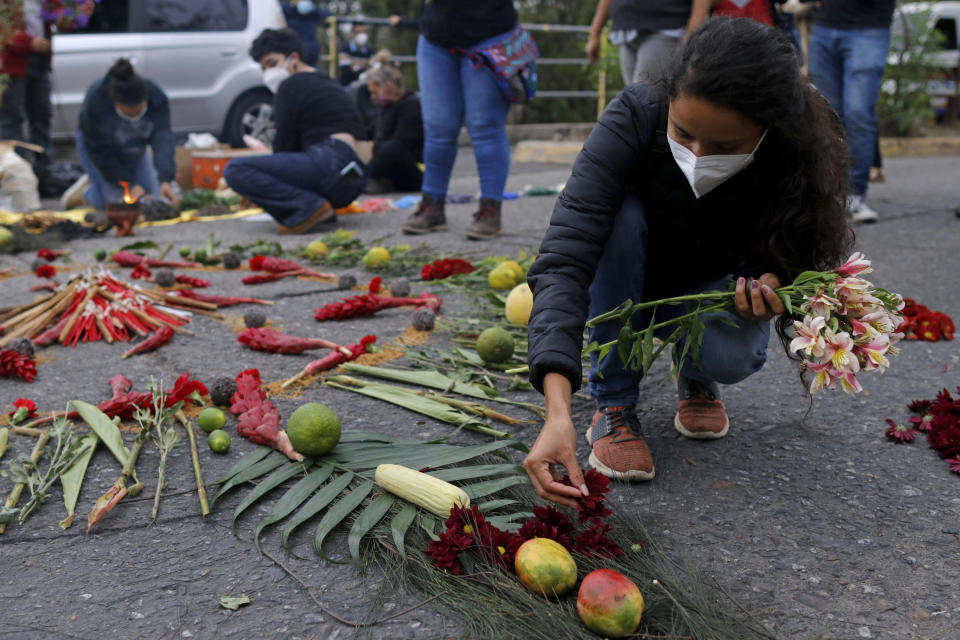Berta Zuniga, a daughter of environmental and Indigenous rights activist Berta Caceres, places flower petal on an offering at a spiritual ceremony, a day before a trial against one of the alleged masterminds of the killing of Caceres, in Tegucigalpa, Honduras, Monday, April 5, 2021. The trial of Roberto David Castillo is expected to run through April. The government has already convicted seven people in Caceres' murder, but is Castillo is considered a potentially critical link to those who ordered it. (AP Photo/Elmer Martinez)