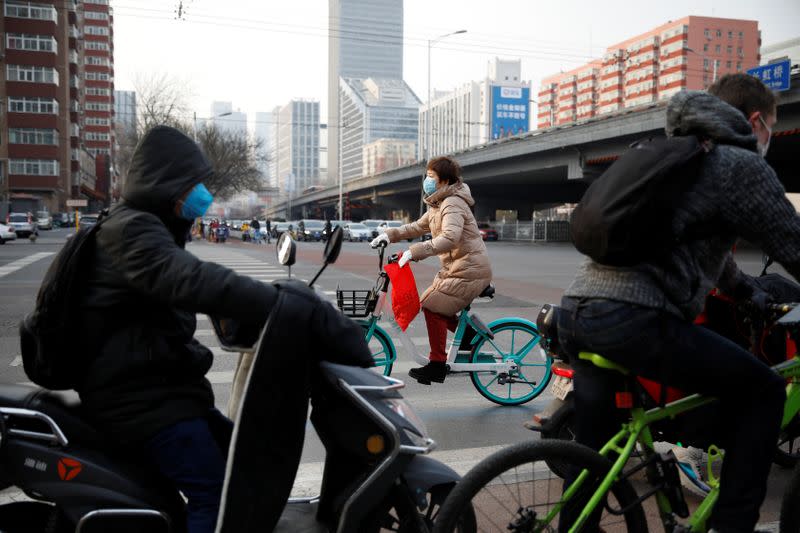 A woman wearing a face mask rides a bicycle on the street, as the country is hit by an outbreak of the new coronavirus, in Beijing