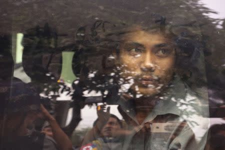 FILE PHOTO: Reuters reporter Kyaw Soe Oo looks out from a police vehicle as he leaves a court in Yangon, Myanmar, December 27, 2017. REUTERS/Stringer/File Photo