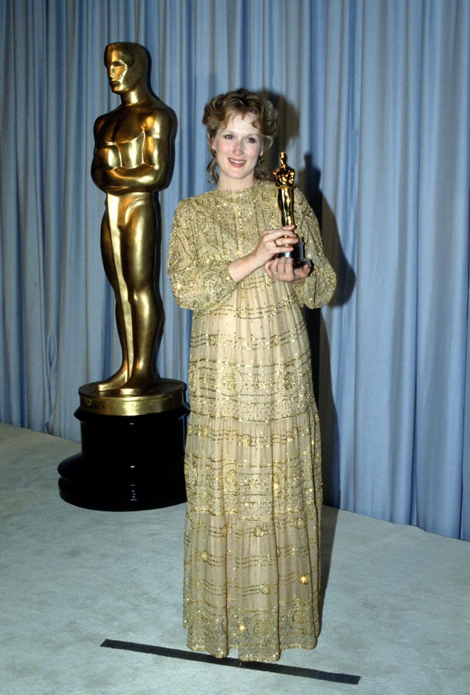 At the Oscars in 1983, Streep won her first Best Actress statue for her role in "Sophie's Choice." For the ceremony, the star (<a href="https://mom.me/entertainment/5965-pregnant-moms-oscar-history/item/meryl-streep_107809696/" target="_blank">pregnant</a>&nbsp;with daughter Mamie Gummer) wore this lovely gold beaded gown -- the perfect choice for taking home the golden&nbsp;award.