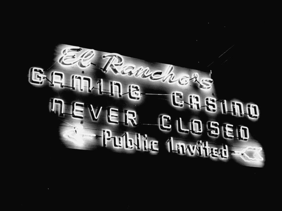A sign showing at night that says El Rancho's Gaming Casino Never Closed with arrow pointing that says Public invited.