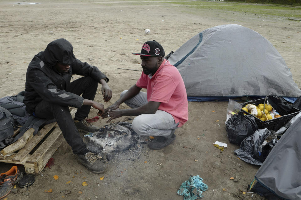 Migrants warm up around a fire in a makeshift camp outside Calais, northern France, Saturday, Nov. 27, 2021. At the makeshift camps outside Calais, migrants are digging in, waiting for the chance to make a dash across the English Channel despite the news that at least 27 people died this week when their boat sank a few miles from the French coast. (AP Photo/Rafael Yaghobzadeh)