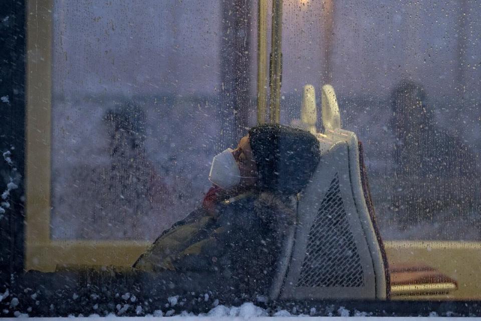 A commuter wearing a mask rests on a TTC street car during a significant dump of snow on Jan. 17, 2022.