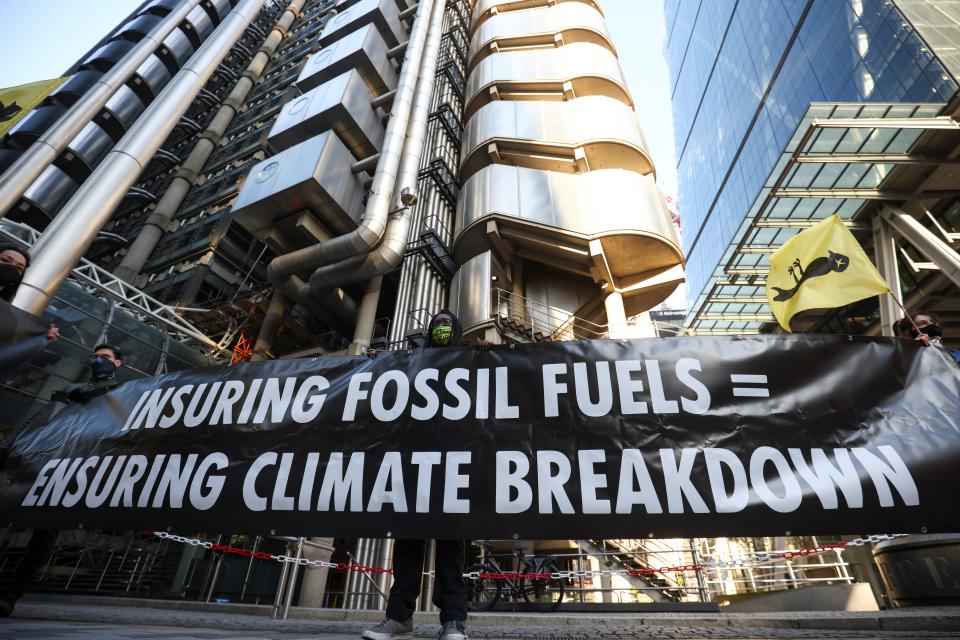 Activists from Extinction Rebellion, a global environmental movement, hold a banner as they protest outside the Lloyd's building in London.REUTERS