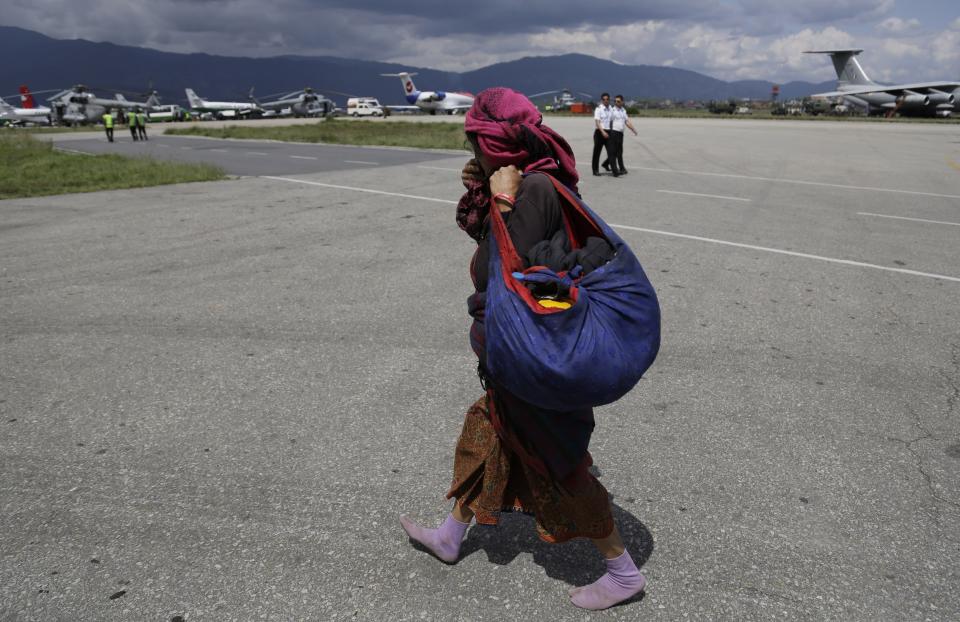 A woman walks barefooted towards the hold area after she was evacuated at the airport in Kathmandu, Nepal, Monday, April 27, 2015. (AP Photo/Altaf Qadri)