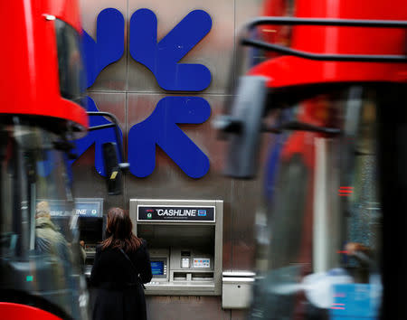 People stand near a branch of Royal Bank of Scotland (RBS) in London, Britain, November 1, 2013. REUTERS/Luke MacGregor/File Photo