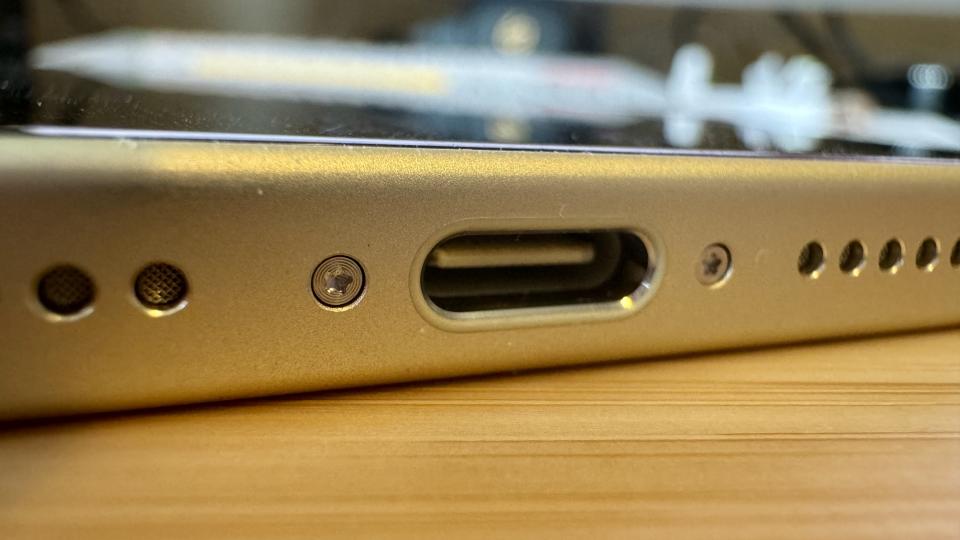 A yellow iPhone 15 on a wooden desk