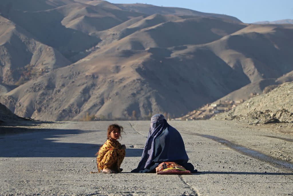  An Afghan burqa-clad woman sits beside a girl, as they look for alms along a street in the Fayzabad district of Badakhshan province . 