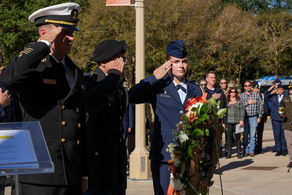 The wreath is saluted as it is laid at the plaza at Royal-Memorial Stadium.