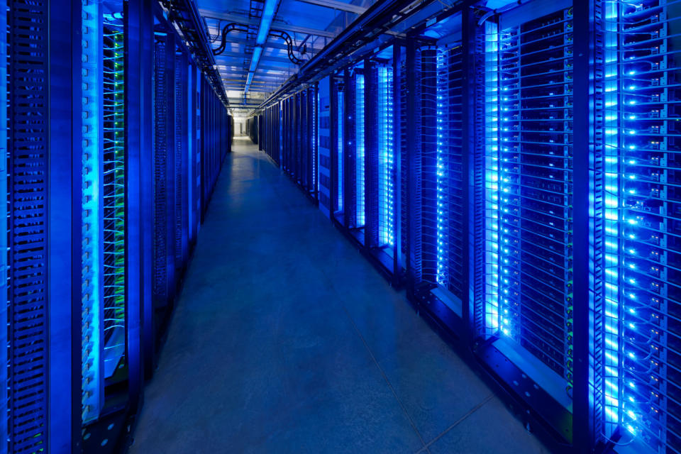 Dark data center room with blue glowing server lights.