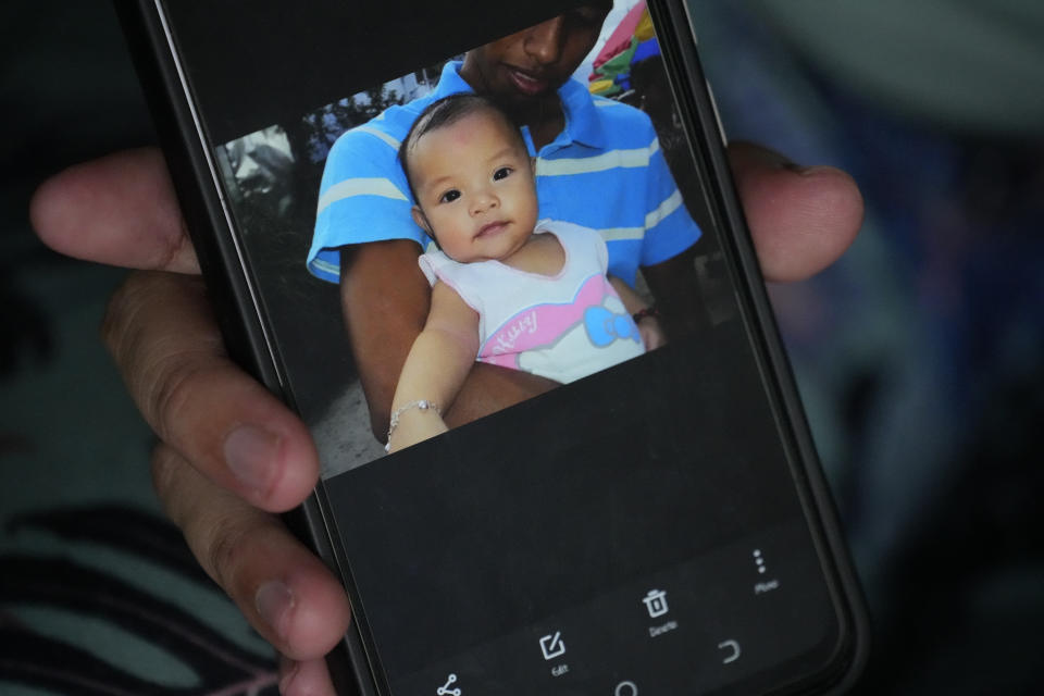 Hyancinth Charm Garing shows a picture of her husband Jeremy with their year-old baby daughter Hywin during an interview in their home at a new community for victims of super Typhoon Haiyan in Tacloban, central Philippines on Sunday Oct. 23, 2022. Garing and his family settled at a relocation site for victims of super Typhoon Haiyan after their village was wiped out when it struck in 2013, killing six family members and their daughter Hywin. (AP Photo/Aaron Favila)