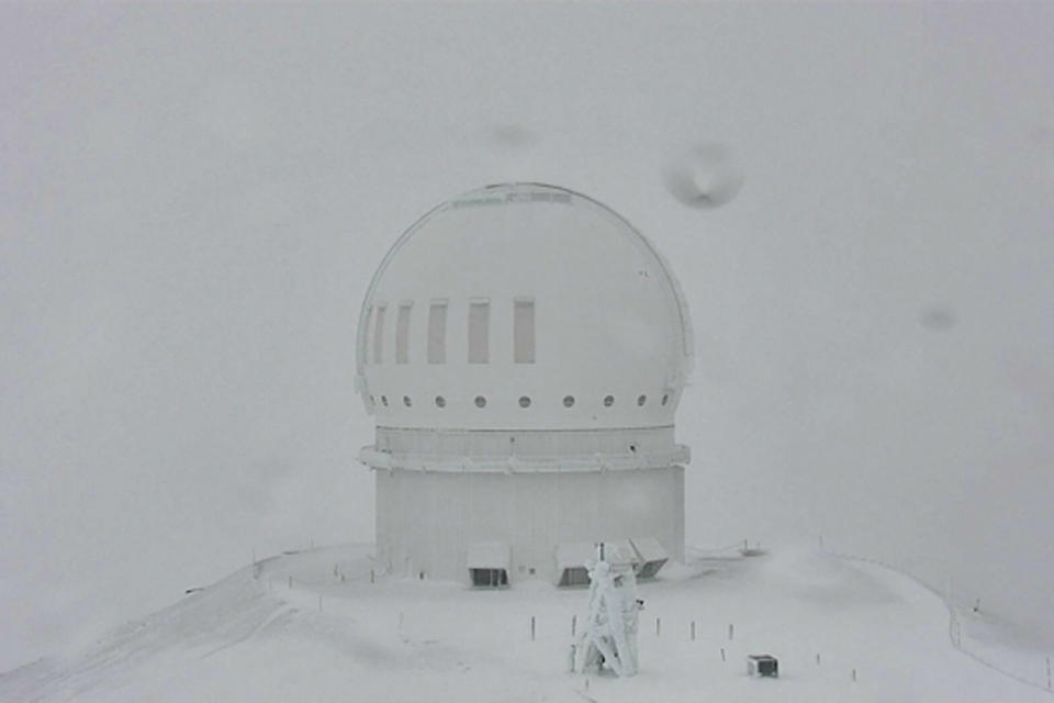 In this webcam image provided by the Canada-France-Hawaiʻi Telescope, snow is seen atop the summit of Mauna Kea in Hawaii on Monday, Dec. 6, 2021. A strong storm packing high winds and extremely heavy rain flooded roads and downed power lines and tree branches across Hawaii. (Canada-France-Hawaiʻi Telescope via AP)